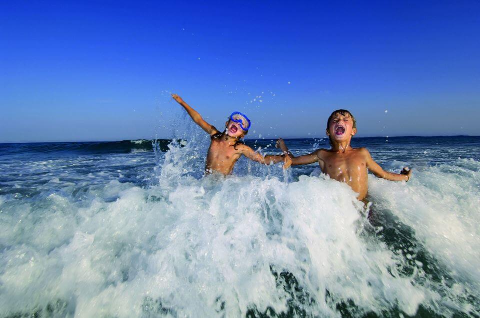 Kinder sind in der Nordsee baden und schwimmen in den Wellen.