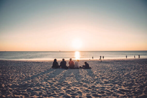 Sehenswürdigkeiten auf Sylt - Eine Gruppe Urlauber sitzt am Strand un schaut sich den Sonnenuntergang an.
