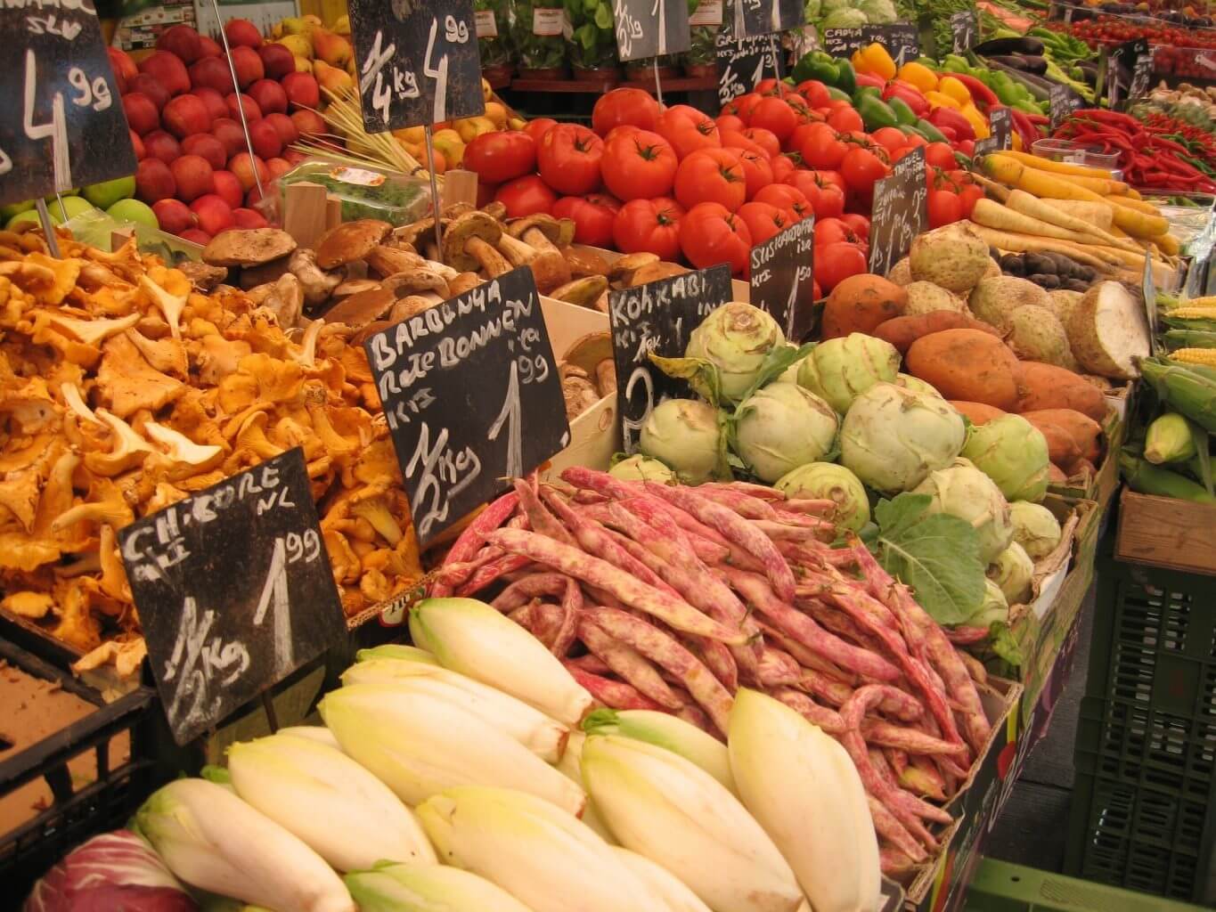 Eine große Auswahl an frischem Obst und Gemüse in Holzkisten mit Preisschildern.